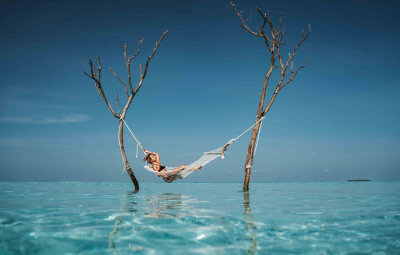 A women relaxing in hammock in the middle of the ocean Fushifaru Maldives resort