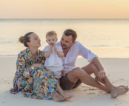 Portrait of family sitting on the beach at Fushifaru Maldives Resort